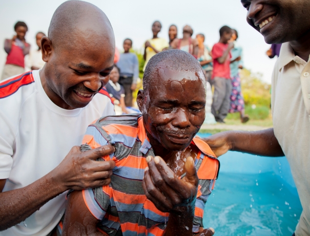 Afrikanische Taufe Zwei Gemeindeleiter taufen einen Christen in Afrika